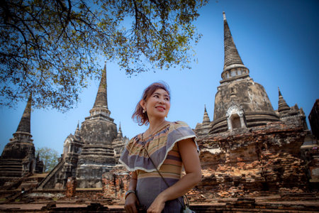 beautiful asian woman smiling with happiness face standing in ancient heritage site of unesco ayutthaya thailandの写真素材