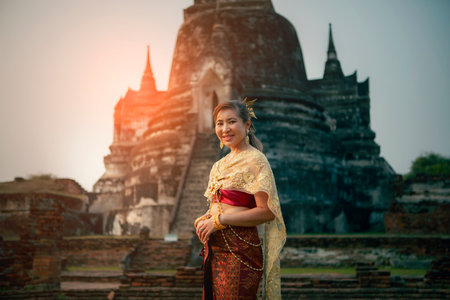 beautiful asian woman wearing thai tradition dress smiling with happiness  standing against old stupa in ayutthaya world heritage site of unesco near bangkok thailandの写真素材