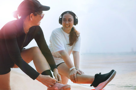 two asian woman stretching muscle and preparing to exercise on sea beach with happinessの写真素材