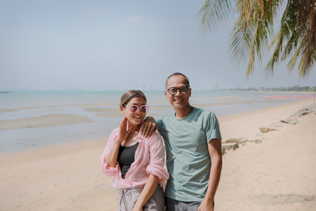 asian couples standing on beautiful sea beach and toothy smiling with happiness faceの写真素材