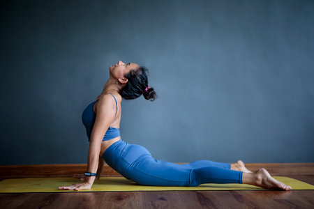 asian woman doing yoga pose in home living home against empty gray wallの写真素材