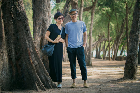 relaxing asian man and woman wearing casual lifestyle standing with relaxing on pine park beachの写真素材