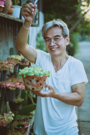 asian holding hanging houseplant pot toothy smiling with happiness face standing outdoorの写真素材