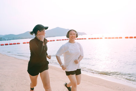 two asian woman running on sea beach with happinessの写真素材