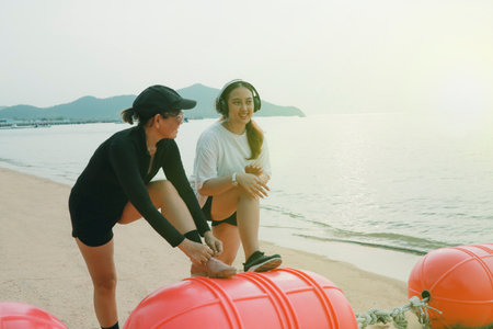 two asian woman stretching before exercise on sea beachの写真素材
