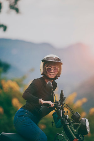woman wearing safety helmet riding small enduro motorcycle against beautiful backgroundの写真素材