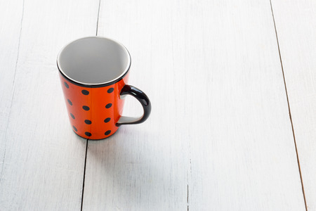 Spotted cup on white wooden backgroundの写真素材