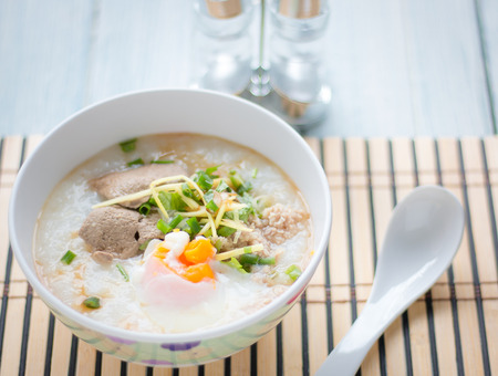 Traditional chinese porridge rice gruel in bowl on white wooden background.の写真素材