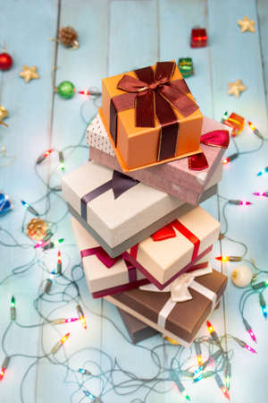 Stack of gift boxes with christmas decorations and christmas lights on cyan wooden background | Top...