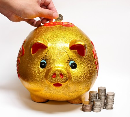 drop coin in gold piggy bank for savingsの写真素材