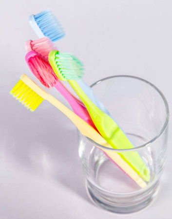 Colorful toothbrushes in a glass on white backgroundの写真素材