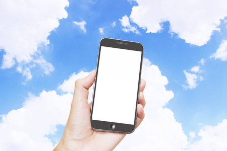 Man hand holding smart phone with isolated white screen,blue sky backgroundの写真素材