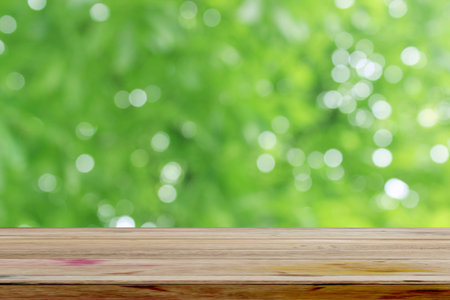 Empty wooden deck table with foliage bokeh background