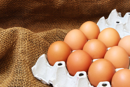 eggs in a carton box on burlap background close upの写真素材