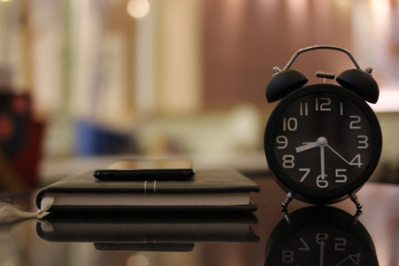 Alarm clock, notebook and pen on the table in the morningの写真素材