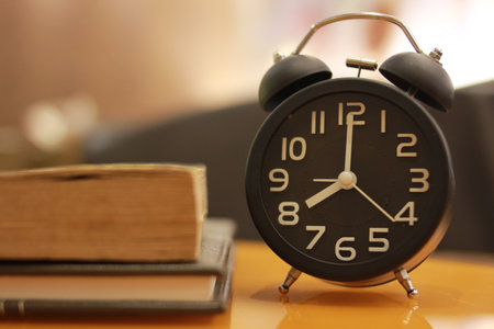 Alarm clock and books on the table in the morning time.の写真素材