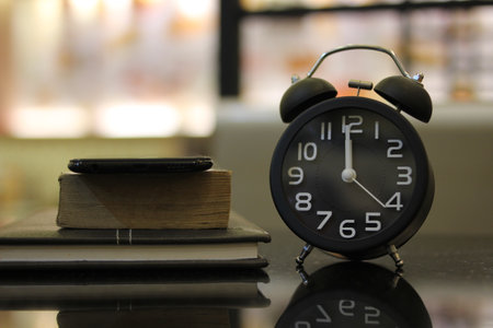 Alarm clock and books on a black table in the library.の写真素材