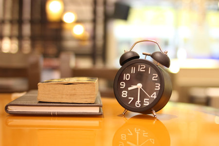 Alarm clock and book on table in coffee shop, stock photoの写真素材