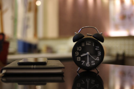 Alarm clock and smartphone on the table in coffee shop blur backgroundの写真素材