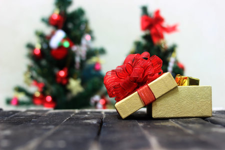 Gift box with red bow and christmas tree on background.の写真素材