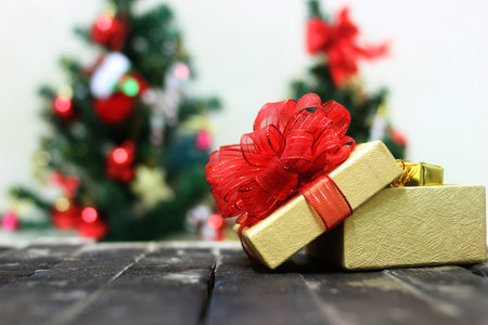 Gift box with a red bow on the background of the Christmas treeの写真素材