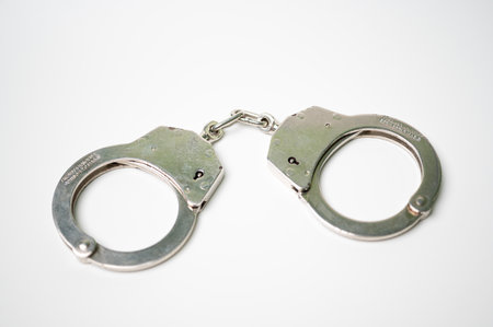 Object is a unilateral handcuff made of iron, single lock, on a white background, symbolizing the law and the offense.の写真素材