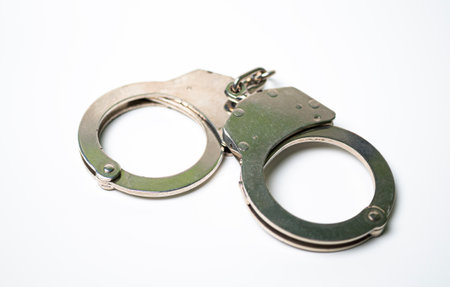 Object is a unilateral handcuff made of iron, single lock, on a white background, symbolizing the law and the offense.の写真素材