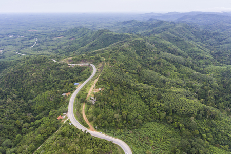 Aerial view of winding road through lush green forests in Nakhon Si Thammarat, Thailand.の写真素材