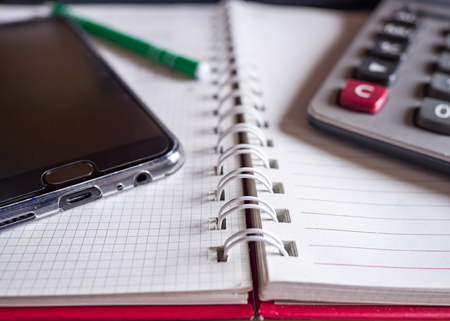 One Smartphone and notebook and calculator on table for meeting and workの写真素材