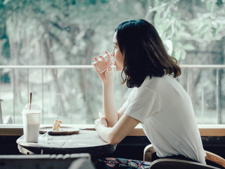 One pretty woman sitting next to the window drinking water, gardenの写真素材