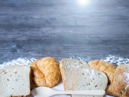 Freshly baked delicious bread and croissant on a wooden worktop with green leave and copy space, healthy eating concept の写真素材