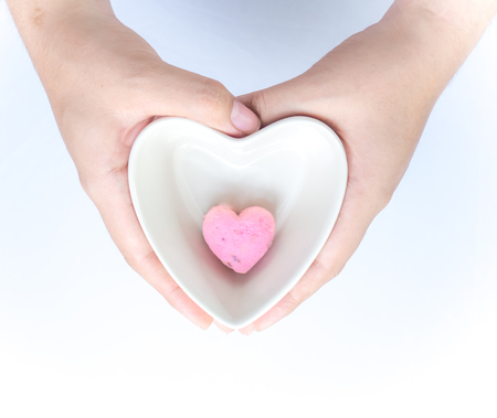 One of Kleeb Lamduan,Thai shortbread cookies heart shape in white ceramic bowl heart shape holding by hand on white background for love issue or valentine's day.の写真素材
