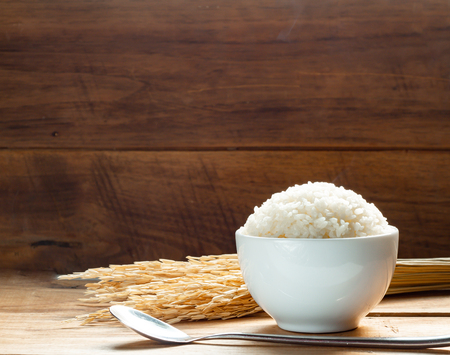 Steam White rice in white ceramic bowl on wood table for healthy meal. Cook concept. Selective focus.の写真素材