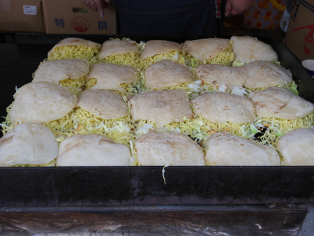 Tokyo, Japan-May 3, 2018: Cooking Hiroshima yaki or Japanese style pancakes on cast-iron panの写真素材