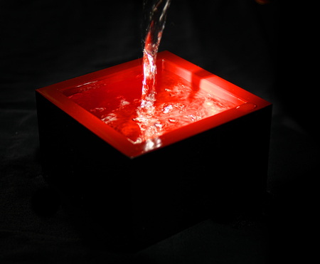 Tokyo, Japan-September 7, 2018: Pouring sake, Japanese traditional alcoholic drink, in a lacquered red container, masu, on black backgroundのeditorial素材