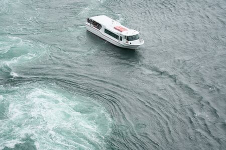 Naruto, Japan-September 28, 2019: The world largest whirlpools in Naruto Channel and a sightseeing boatの写真素材