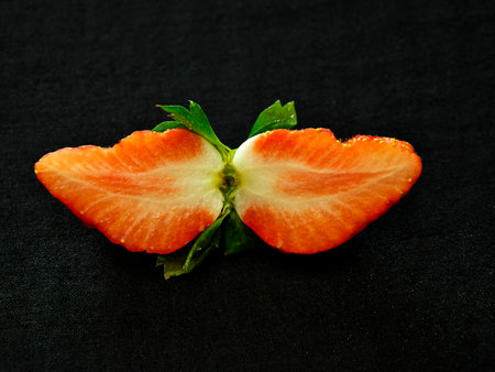 Fresh and juicy sliced strawberry on black backgroundの写真素材