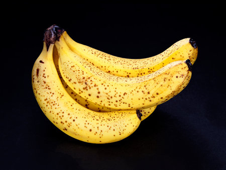 Tokyo,Japan - August 15, 2022: Hands of ripe bananas with black spots on black backgroundの写真素材