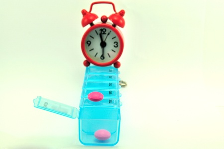 Pill box and red clock show medicine timeの写真素材