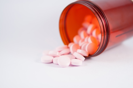 Pink tablet and brown bottle on white backgroundの写真素材