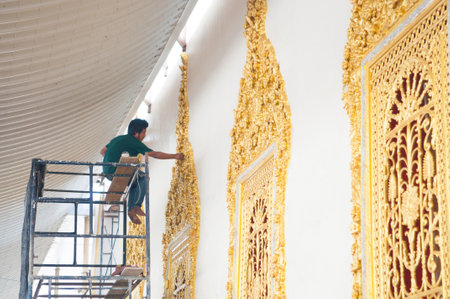 Men painting gold texture in temple of Thailandのeditorial素材