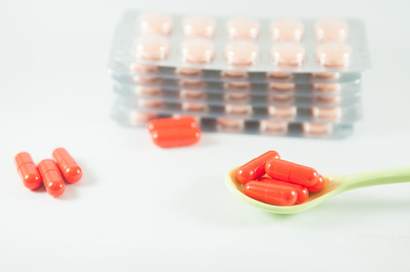 Orange capsule in spoon on blister pack backgroundの写真素材
