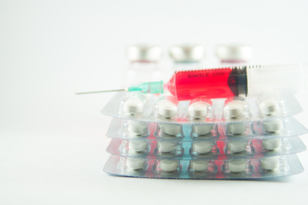 Red liquid in disposable syringe on blister pack and medication backgroundの写真素材