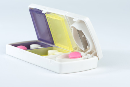 Closed up aluminum blade and pink tablet in pill boxの写真素材