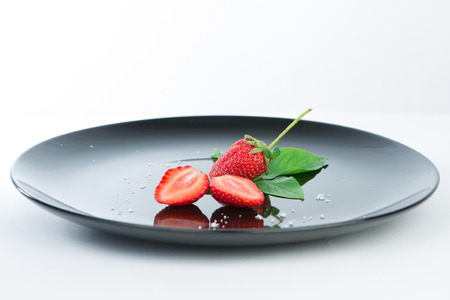Fresh of half strawberry on black dish and reflexの写真素材