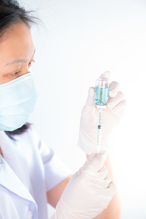 Closed up Nurse fills syringe from injection vial on whiteの写真素材