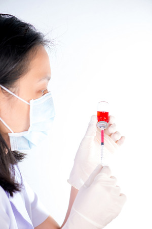 Nurse fills syringe from injection vial on whiteの写真素材