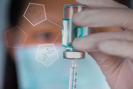 Closed up Nurse fills syringe from injection vial and chemical structure buttonsの写真素材