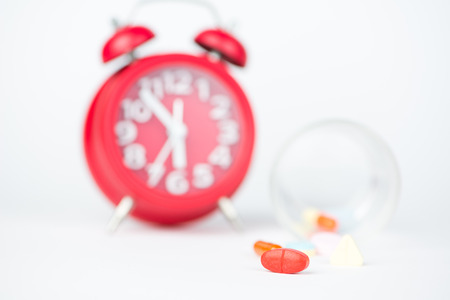 Medicine tablet, dispensing glass and red clock show medicine time