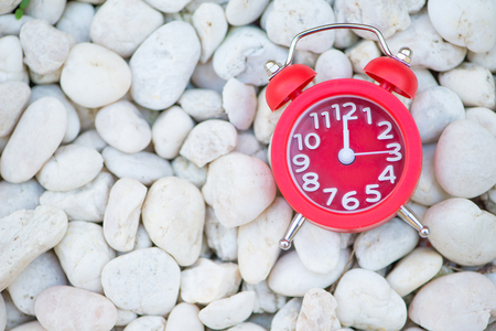 Red alarm clock on white rock